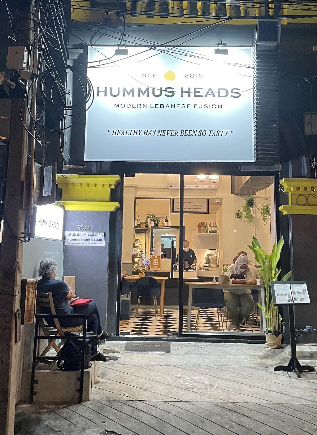 Hummus Heads Silom storefront and entrance, lit up at night