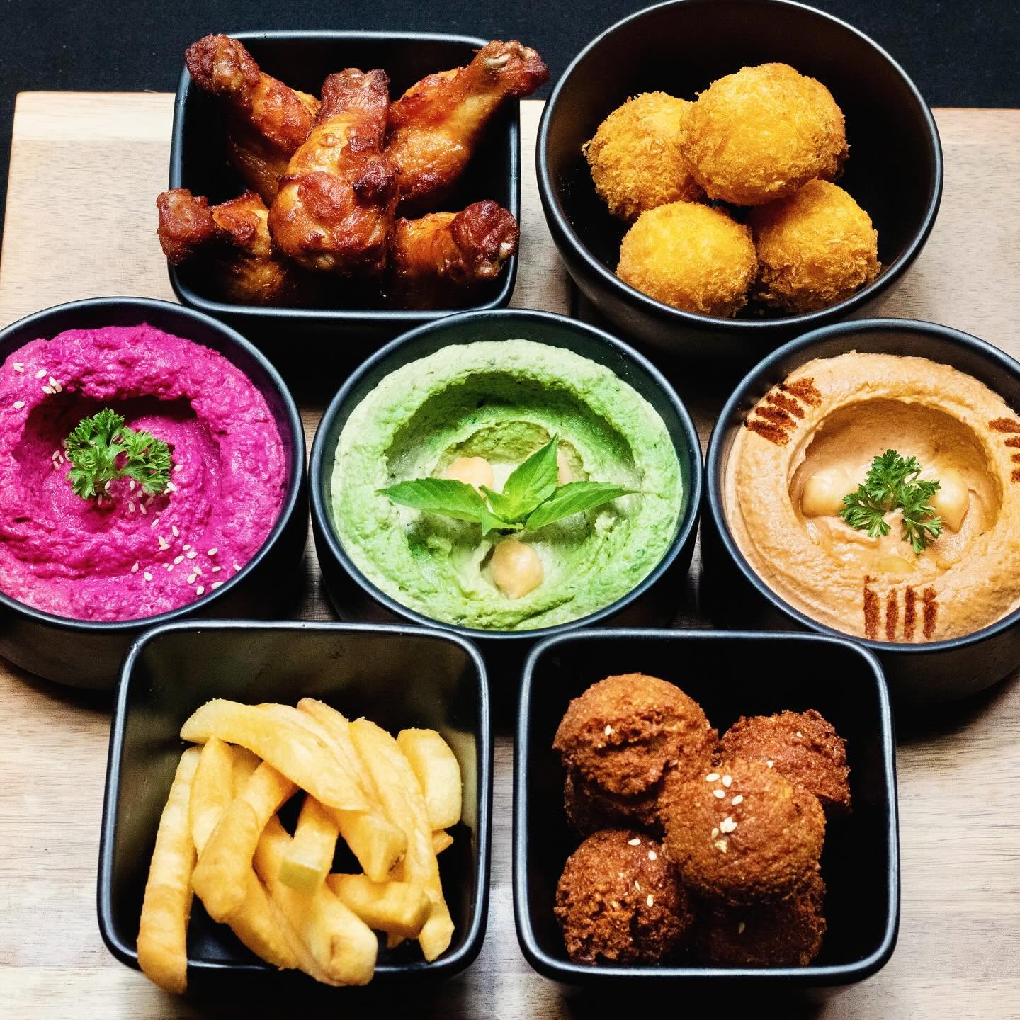 A full table spread of hummus, fattoush, falafel and sandwiches at Hummus Heads